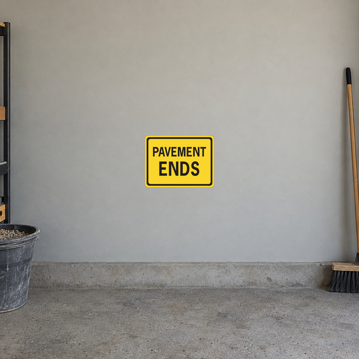Road Sign Sticker applied in a continuous warm grey garage wall with gravel bucket and push broom at extreme sides
