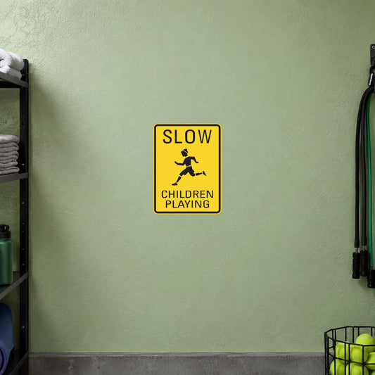 Yellow road sign sticker reading “SLOW CHILDREN PLAYING” with child icon.