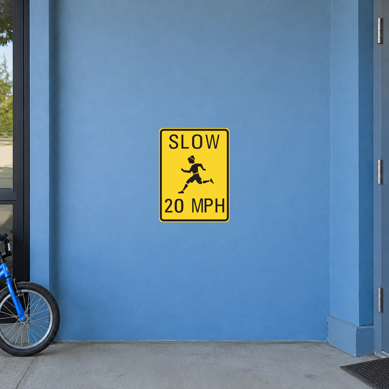 Road Sign Sticker applied in a continuous soft blue school service entrance wall, child size bicycle wheel at far left bottom