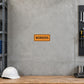 Road Sign Sticker applied in a continuous pale grey concrete tool room wall, hard hat on bench at far bottom edge