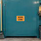Road Sign Sticker applied in a smooth deep teal single road crew workshop cupboard, broom and gloves at far edges