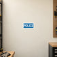 Road Sign Sticker applied in a continuous warm ivory traffic maintenance room wall with work gloves at bottom left edge
