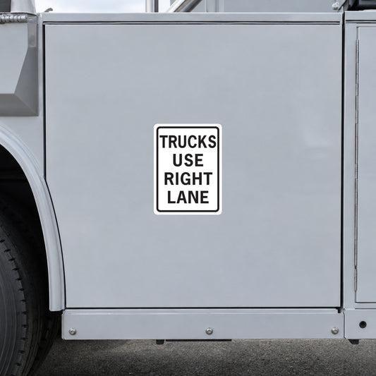Road sign sticker with black text reading "TRUCKS USE RIGHT LANE" on a square sign