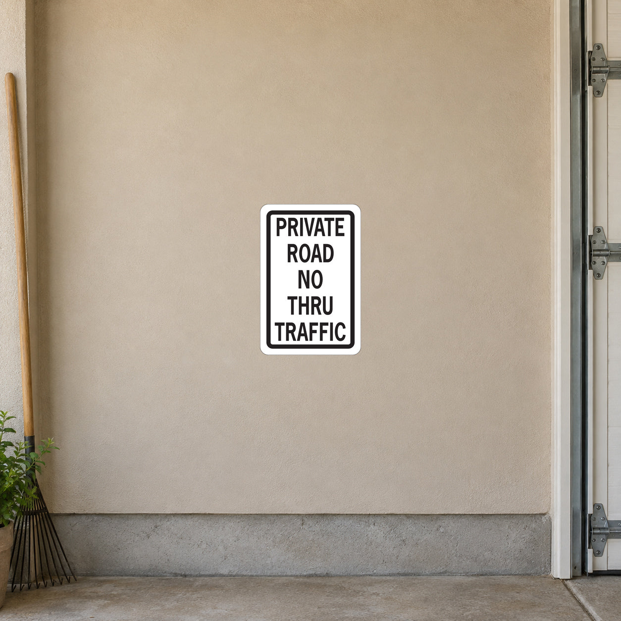 Road Sign Sticker applied in a continuous sandy beige private estate garage wall, garden rake far left edge