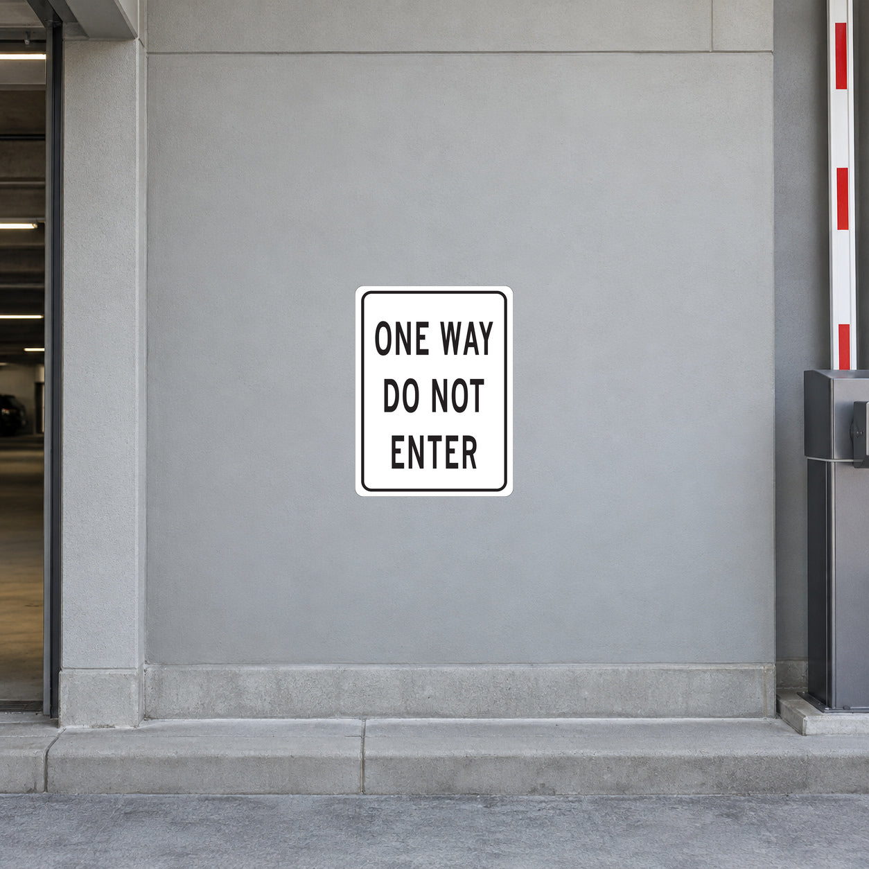 Road Sign Sticker applied in a continuous light grey parking garage entrance wall with curb at bottom and barrier arm at far right