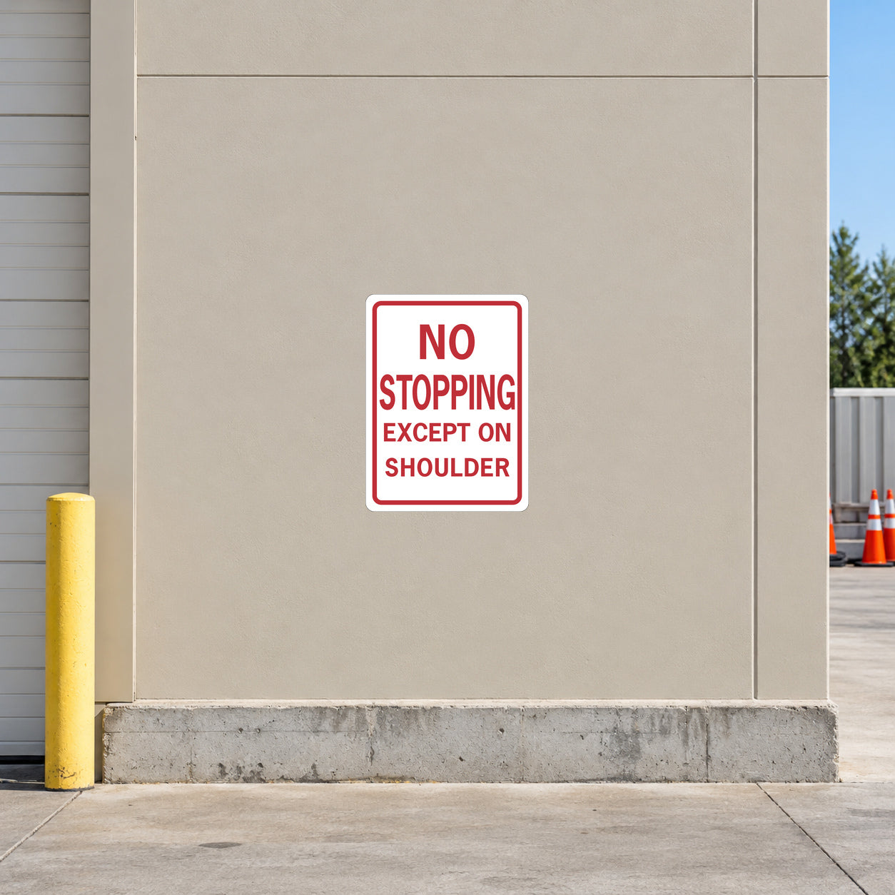 Road Sign Sticker applied in a continuous light tan highway depot wall, safety cones far right and concrete curb below