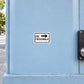 Road Sign Sticker applied in a continuous pale blue pedestrian walkway wall, crossing button housing at far RIGHT edge, blank central surface for right pointing crosswalk instruction
