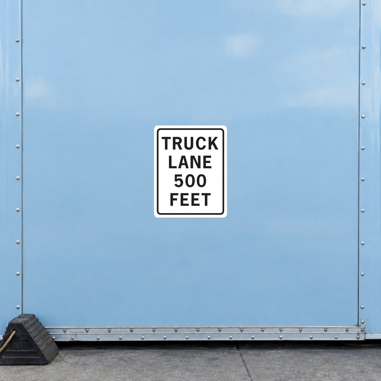 Road Sign Sticker applied in a continuous pale blue freight dispatch wall with wheel chock at bottom left edge