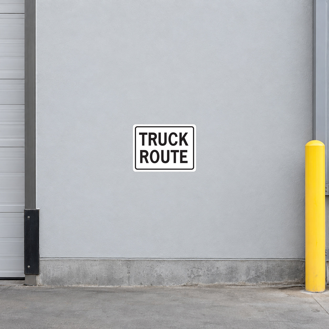 Road Sign Sticker applied in a continuous light grey truck service entrance wall with protective post at far right