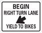 Road sign sticker with white rectangle and black text: BEGIN, RIGHT TURN LANE, YIELD TO BIKES