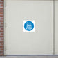 Safety Sign Sticker applied in one broad flat cream steel leaf of a closed pair of warehouse doors, meeting seam at extreme right edge, brick jamb left, industrial overhead fittings outside frame