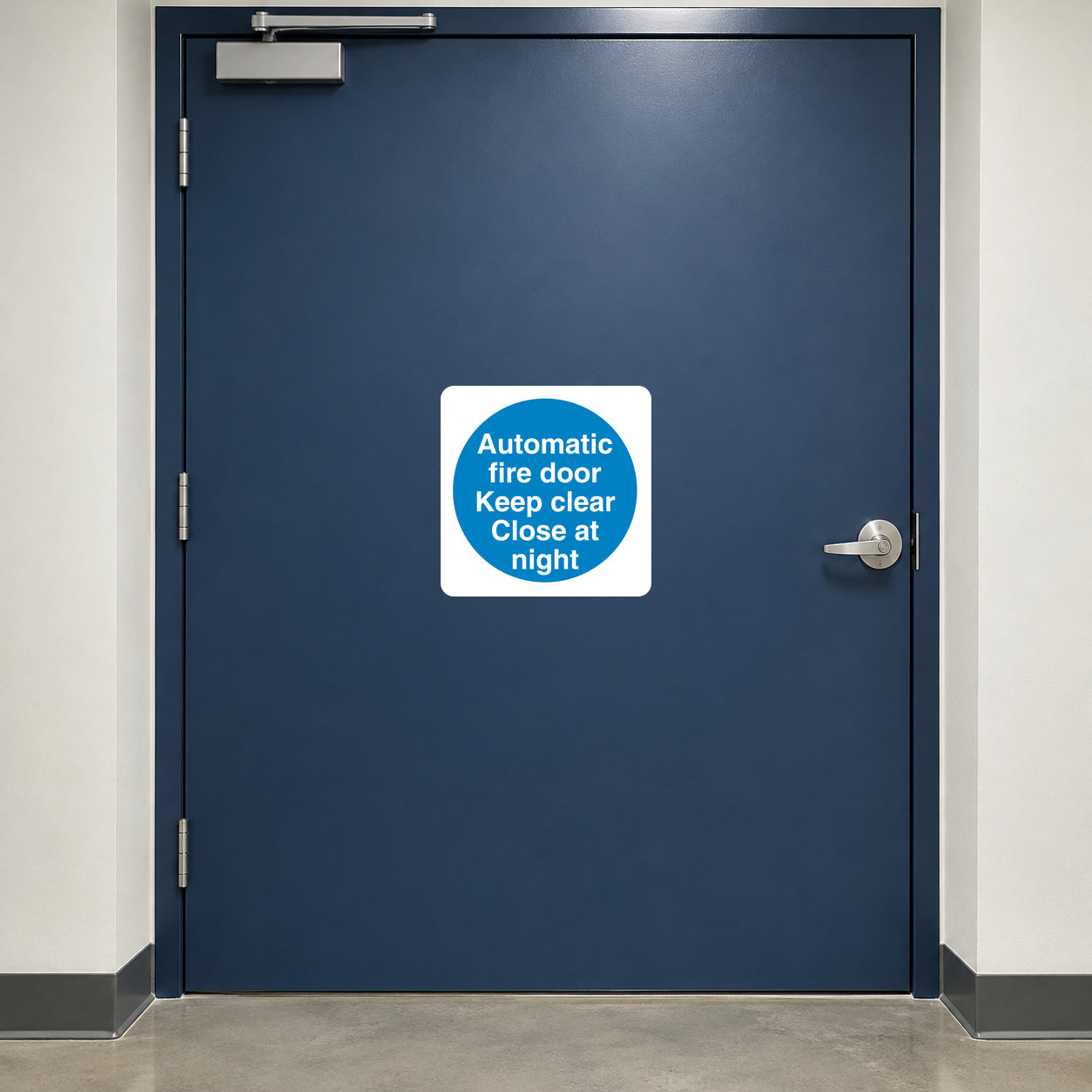 Safety Sign Sticker applied in a closed automatic fire door broad flat dark blue face in a commercial corridor, overhead closer at very top edge and handle extreme right, no central window or seam