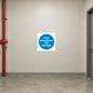 Safety Sign Sticker applied in a smooth cream wall in a clear building service corridor reserved free of storage, doorway extreme right and red fire pipe far left, empty floor below