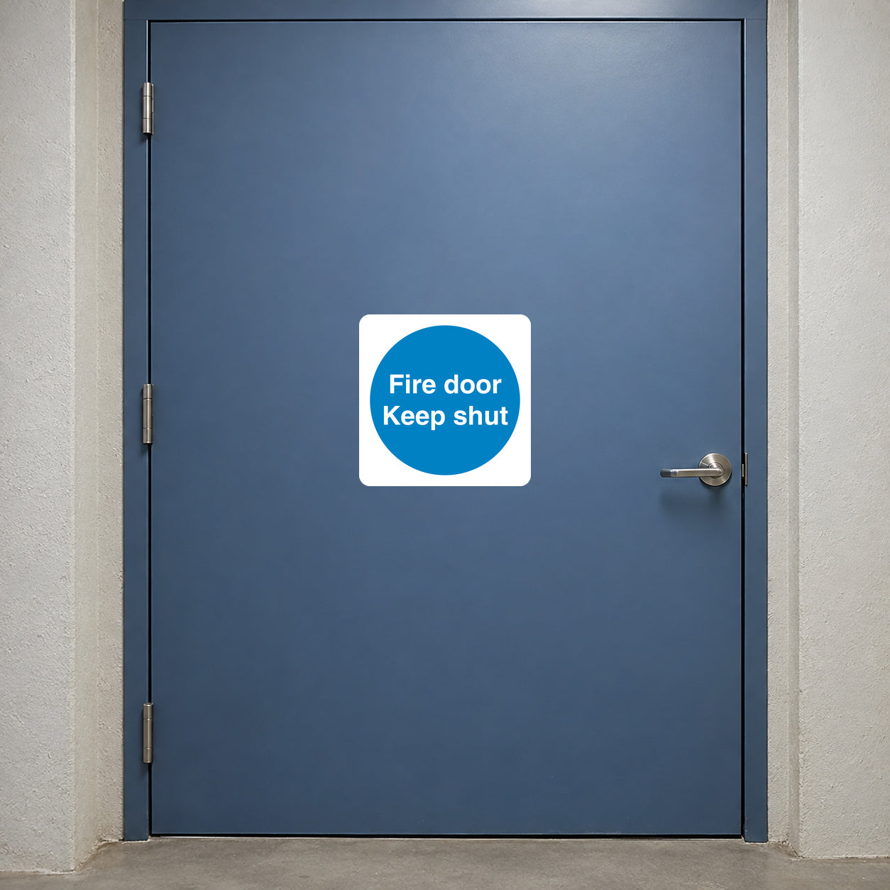 Safety Sign Sticker applied in a closed smooth muted blue fire door at an apartment service passage, hinge extreme left and latch far right, broad central uninterrupted face