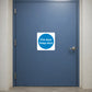Safety Sign Sticker applied in a closed smooth muted blue fire door at an apartment service passage, hinge extreme left and latch far right, broad central uninterrupted face