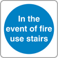Blue circular fire safety sign sticker with text: In the event of fire use stairs