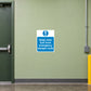 Safety Sign Sticker applied in a smooth pale green wall by a rear workshop emergency escape door, clear route below and door frame extreme left
