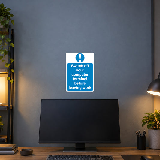 Safety Sign Sticker applied in Blue grey office wall above a desktop computer, monitor only below y85%, keyboard and desk corner at bottom, quiet evening light
