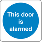 Safety sign sticker: 'This door is alarmed' on blue circle