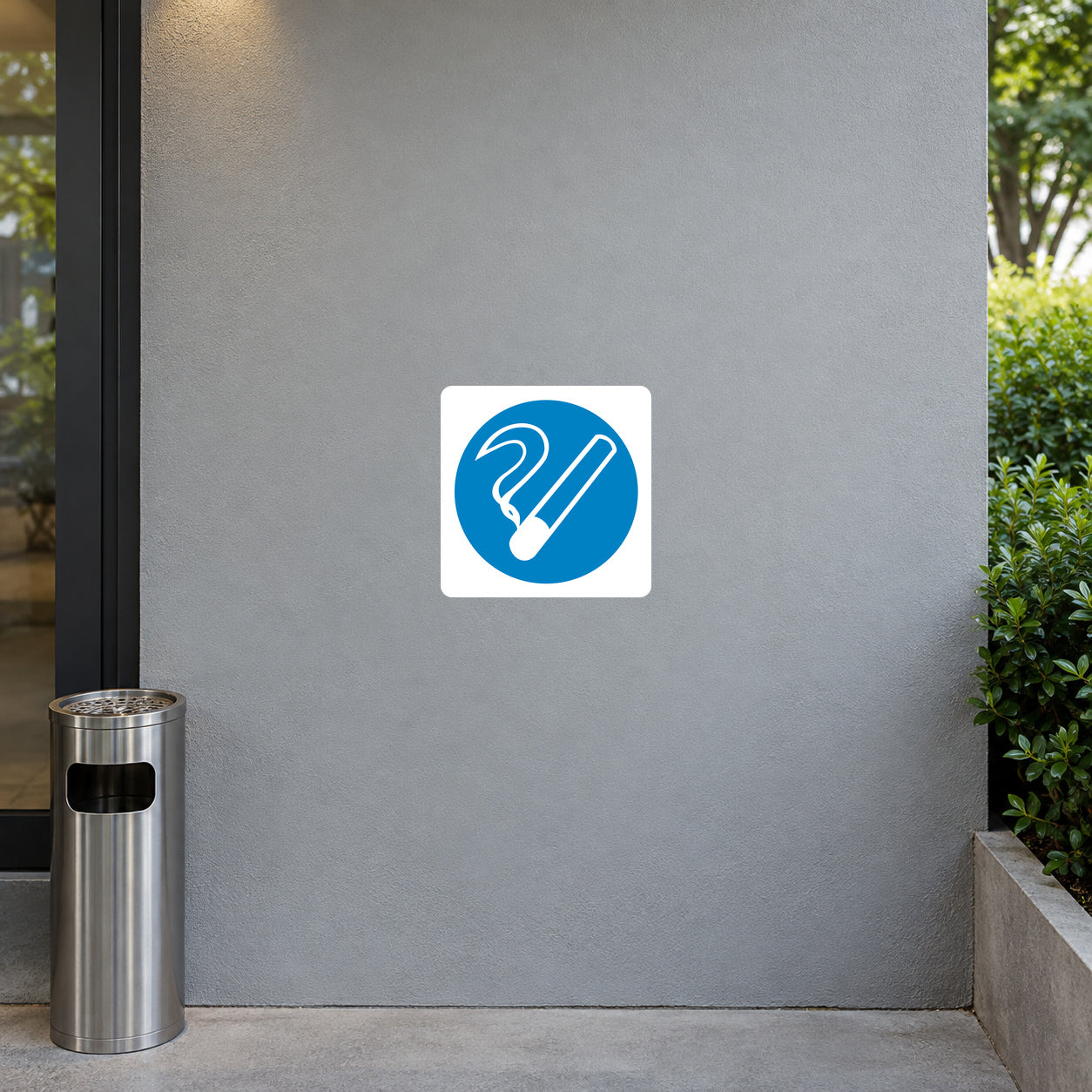 Safety Sign Sticker applied in Smooth grey outdoor designated smoking alcove wall, brushed steel ashtray pedestal far lower left below y85%, garden edge at far right