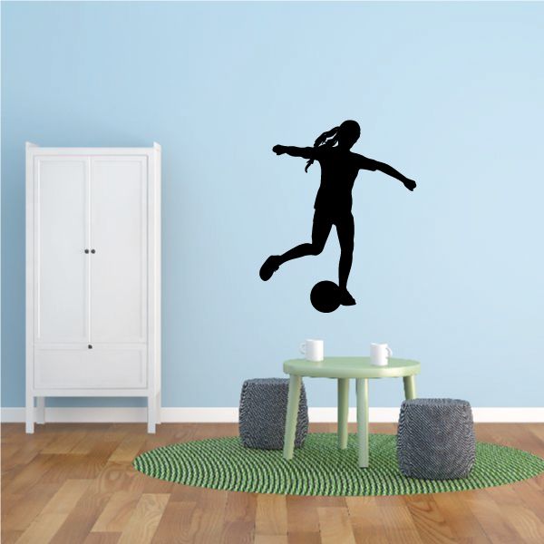 Soccer wall decal of black soccer player silhouette in mid-kick on light blue wall.