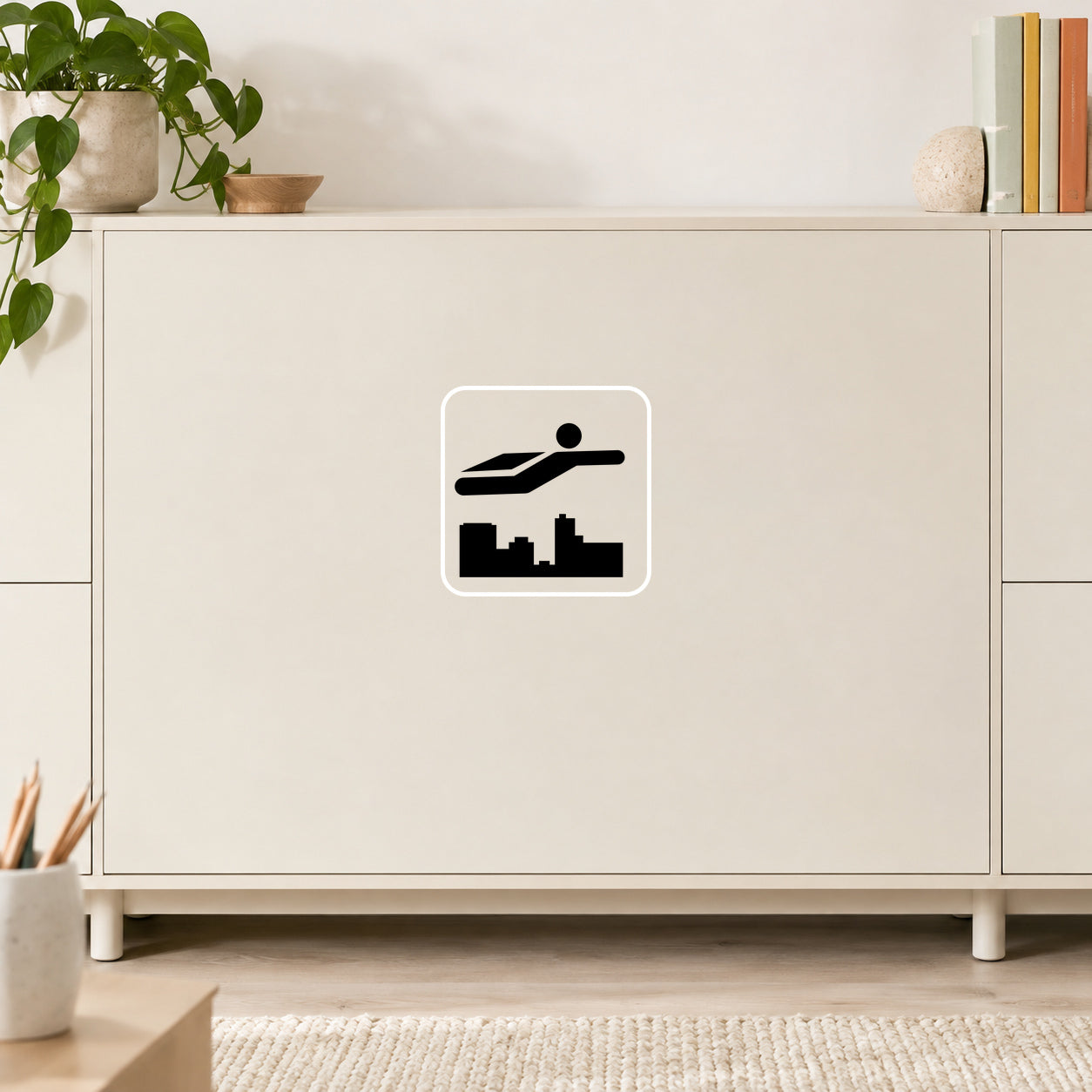 Super Hero Sign Decal applied in Smooth light cream creative studio equipment cabinet, coloured books at far right edge and pencils at extreme bottom left, bright room