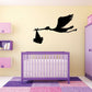 Black stork carrying baby bundle wall decal above a crib