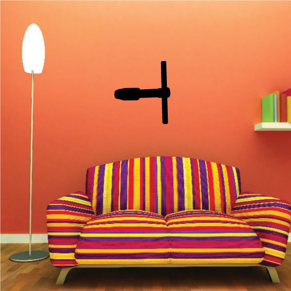 Black T-shaped tap wrench decal shown on an orange wall above a striped sofa
