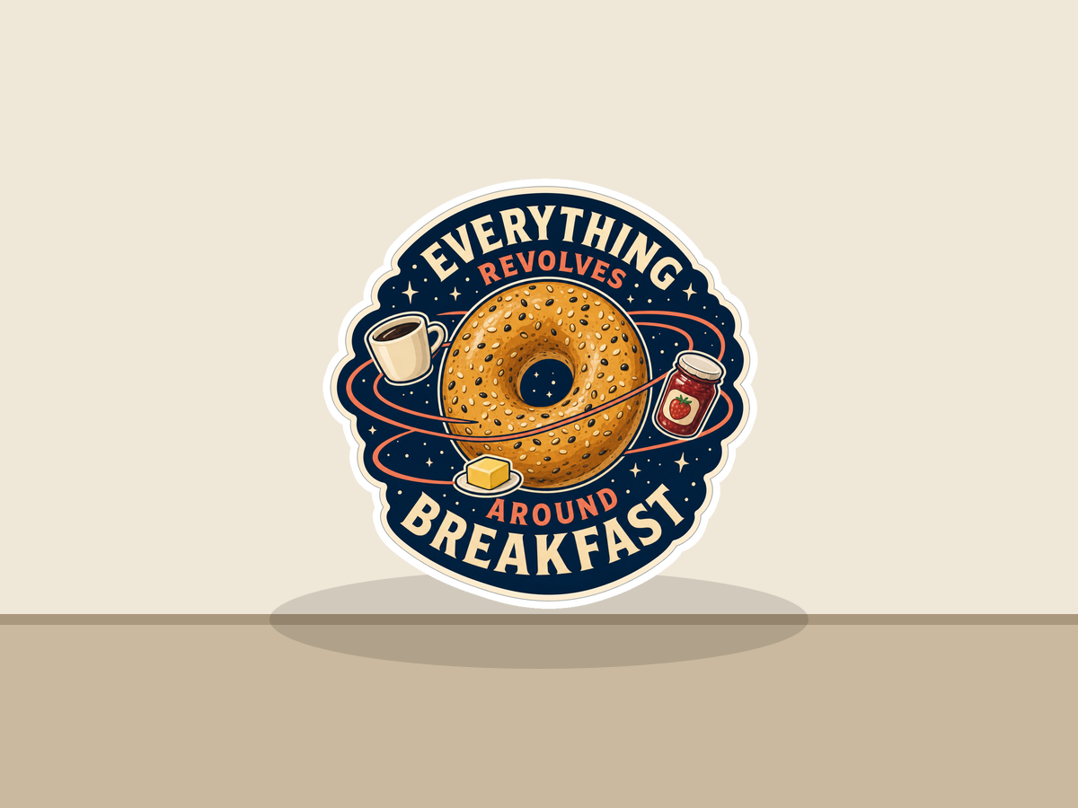 Round sticker with donut, coffee cup, and jam jars; reads “EVERYTHING REVOLVES” “AROUND BREAKFAST”.