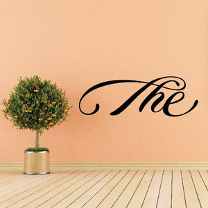 Cursive wall decal reading 'The' in black with decorative swirls