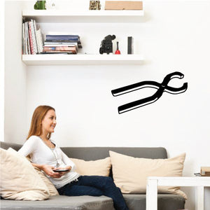 Black tongs wall decal with two hinged tong arms and circular ring handle.