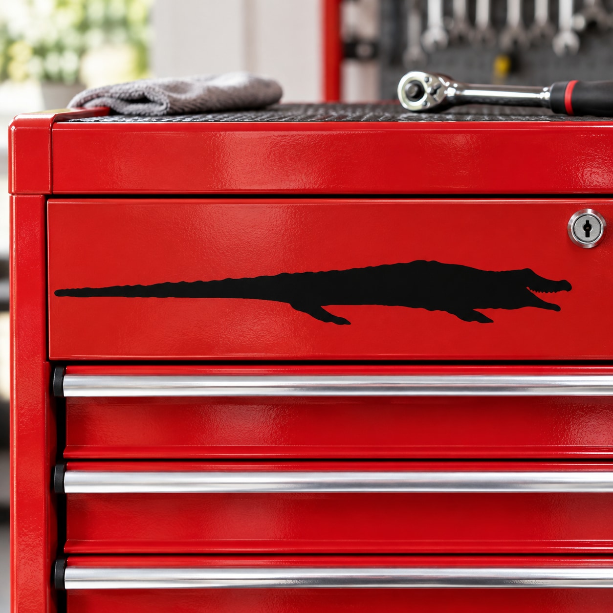 Black stretched alligator graphic decal on red metal toolbox drawer