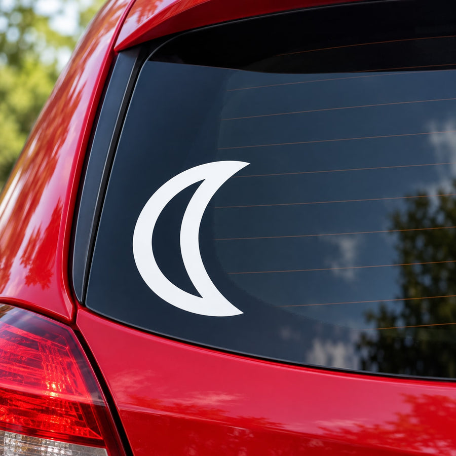 White crescent moon crest decal on dark car window glass