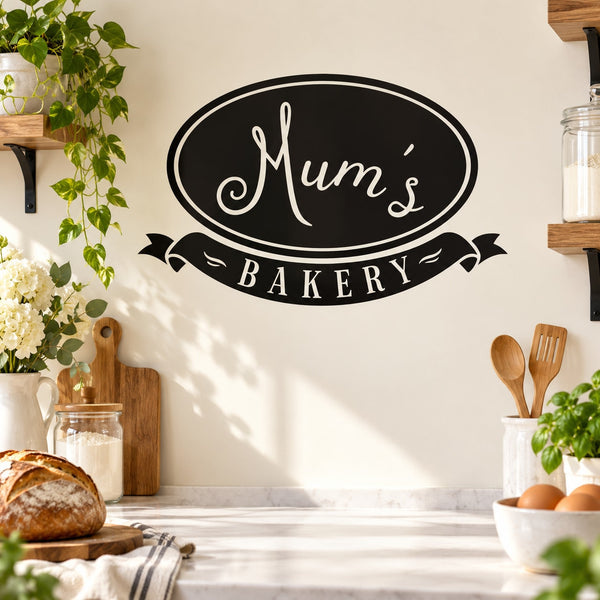 Black oval Mum's Bakery wall decal with white script and ribbon banner