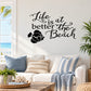 Beach wall decal with black cursive text and surfboard-and-fish graphic
