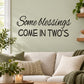 Black wall decal with script and bold text: "Some Blessings Come In Twos"