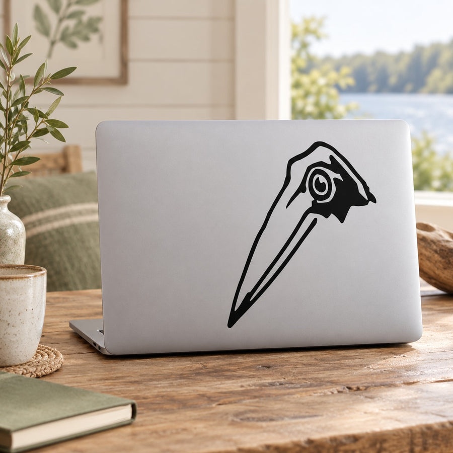 Heron head vinyl decal with black line art on light laptop lid