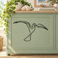 Black shore bird wall decal with wings spread, outlined on a light green cabinet
