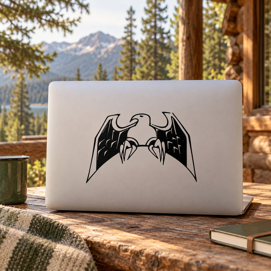 Perched eagle decal with black mirrored wings on a light gray laptop