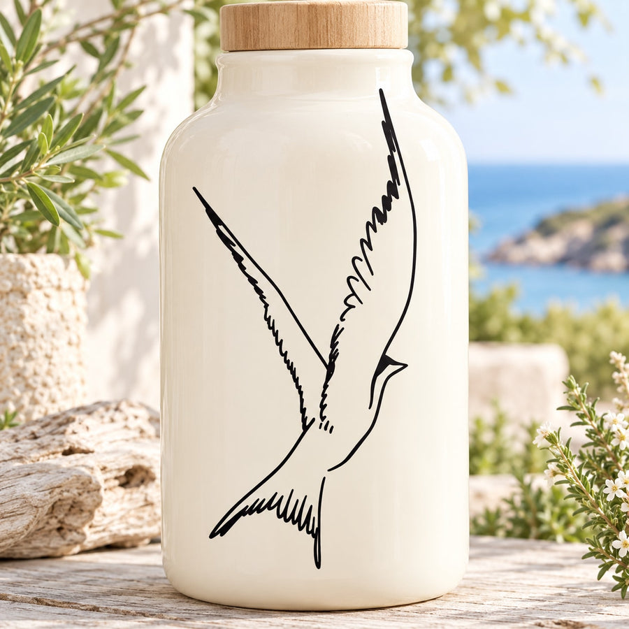 Black flapping swallow decal on front of clear glass bottle with wooden lid