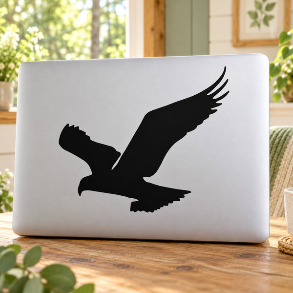 Black falcon flapping-wing decal on a white laptop lid