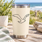 Black line-art flying shore bird decal on light beige tumbler
