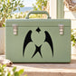 Black heart-and-swallow style decal on a green suitcase front