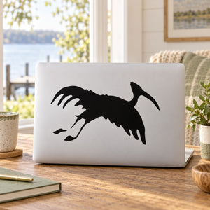 Black stork decal with flapping wings on a laptop lid
