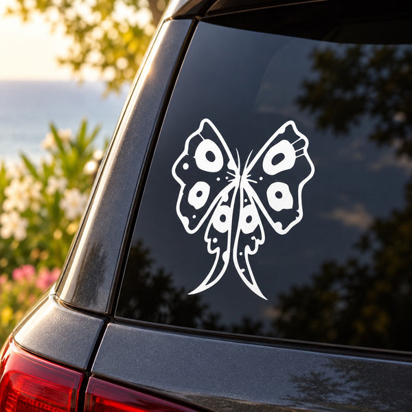 White butterfly vinyl decal on a car rear window, outlined in black details.