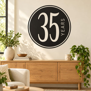 Round black 35 years celebration wall decal with white border and vertical text.