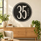 Round black 35 years celebration wall decal with white border and vertical text.
