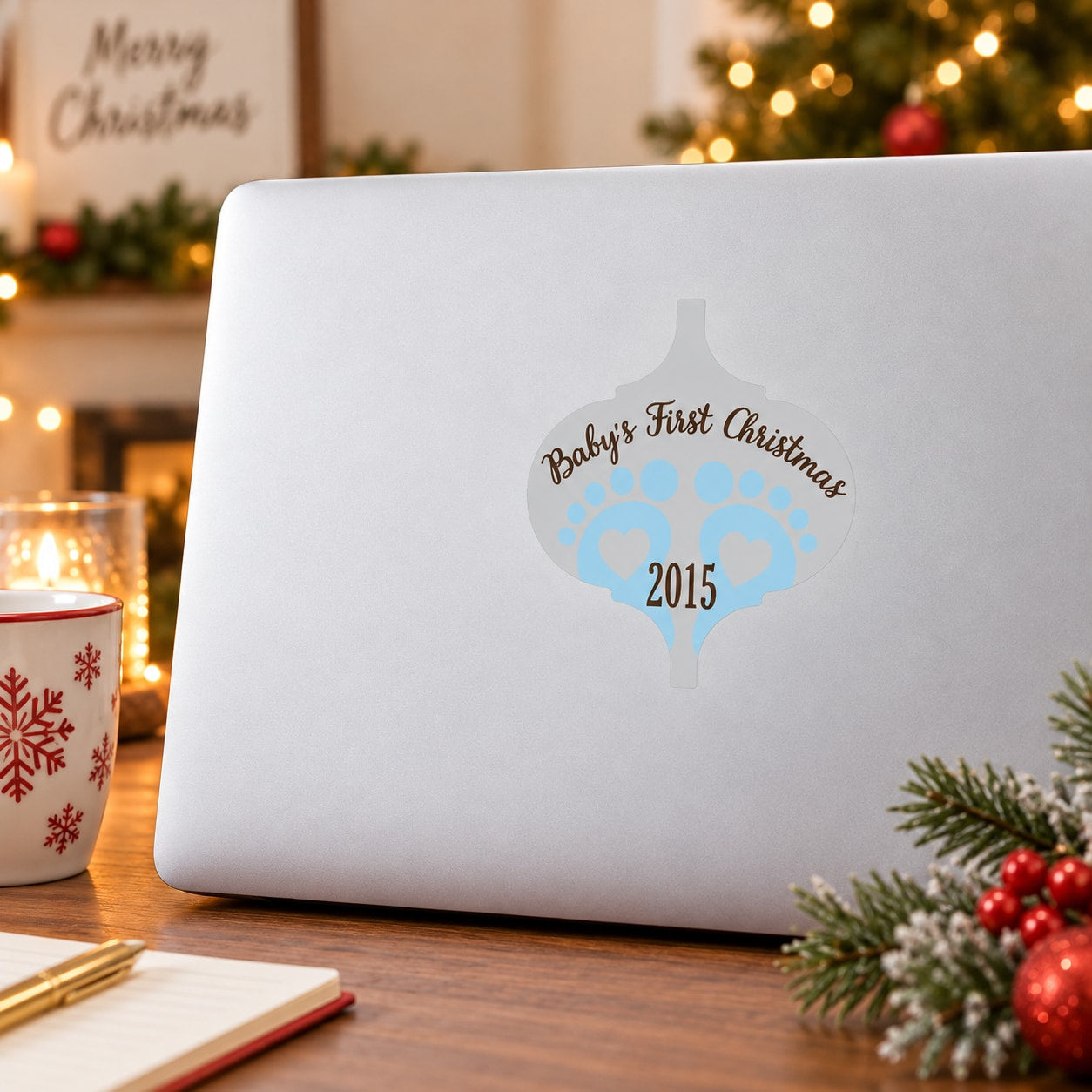 White ornament sticker with baby feet print, “Baby's First Christmas” and year 2015