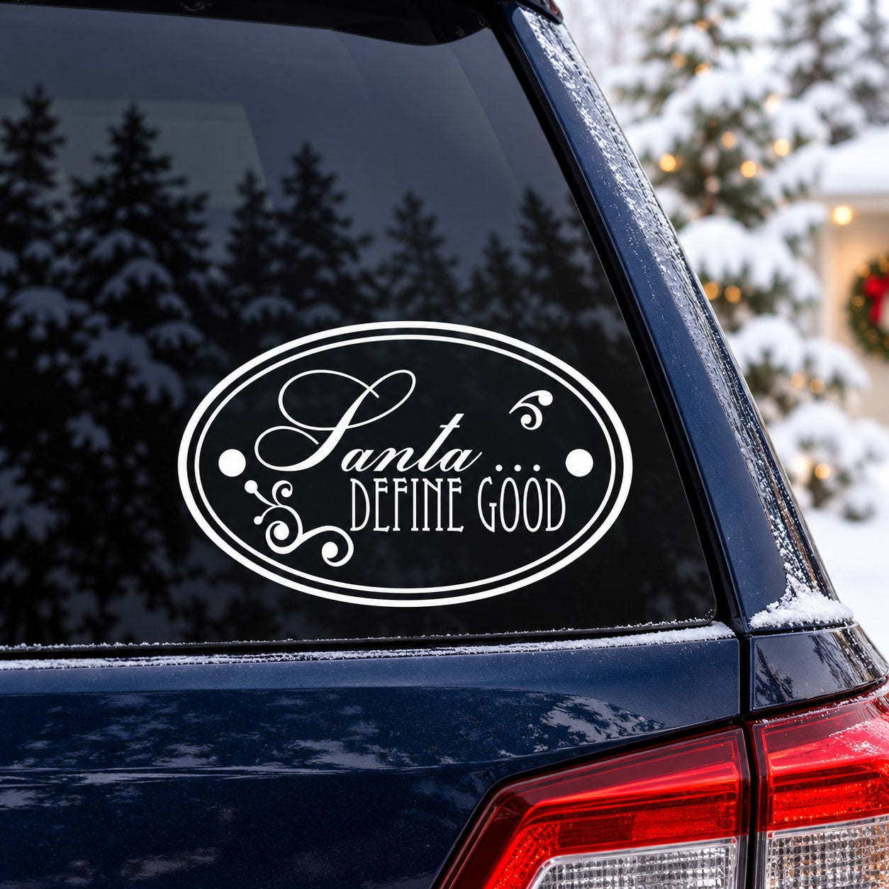 Oval white "Santa Define Good" decal with decorative swirls on dark window