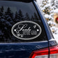 Oval white "Santa Define Good" decal with decorative swirls on dark window
